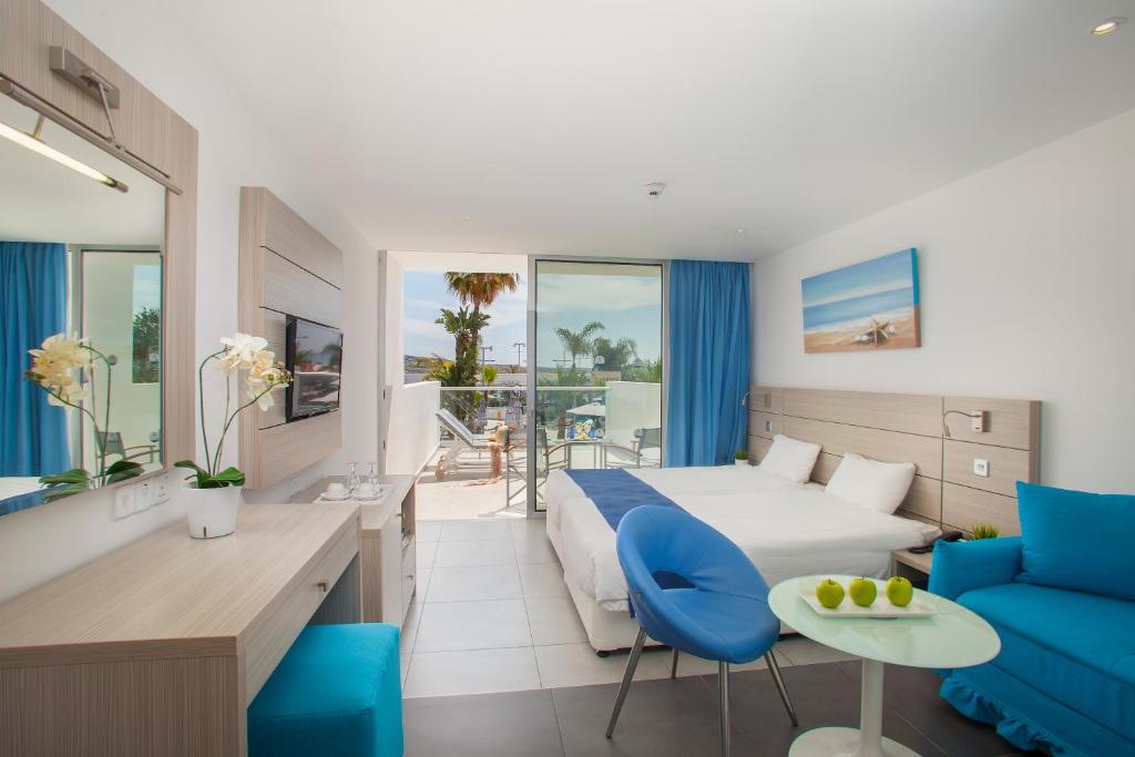 a hotel room with a bed and a blue couch at Limanaki Beach Hotel & Suites in Ayia Napa