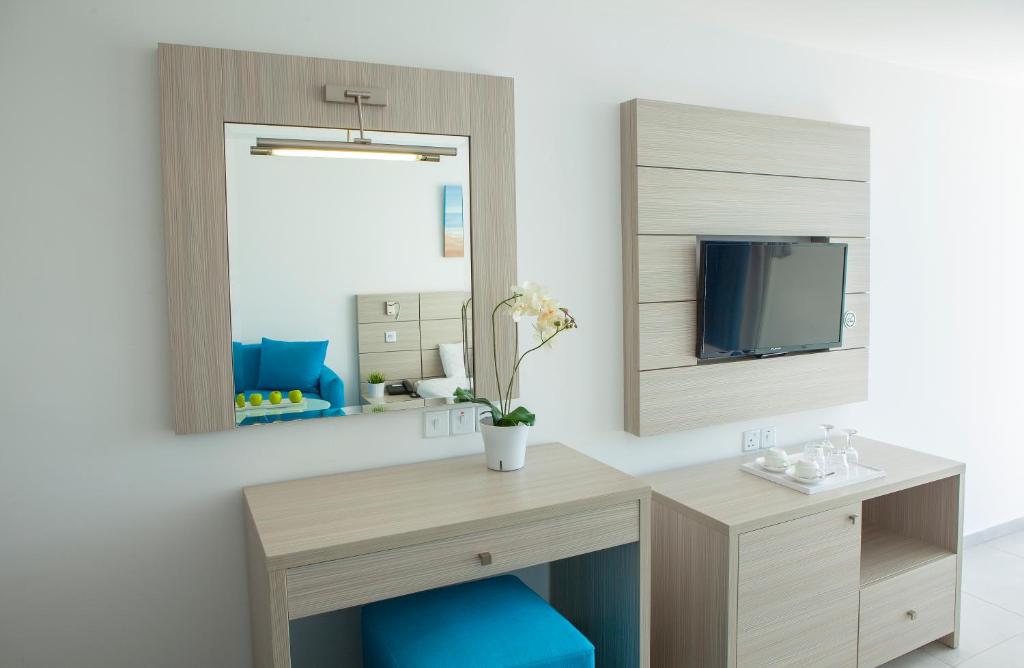 a room with a desk and a mirror at Limanaki Beach Hotel & Suites in Ayia Napa