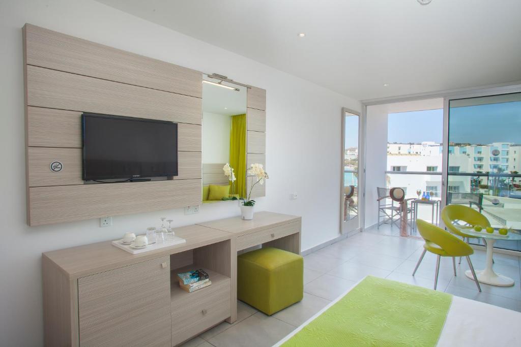 a living room with a tv on a wall at Limanaki Beach Hotel & Suites in Ayia Napa
