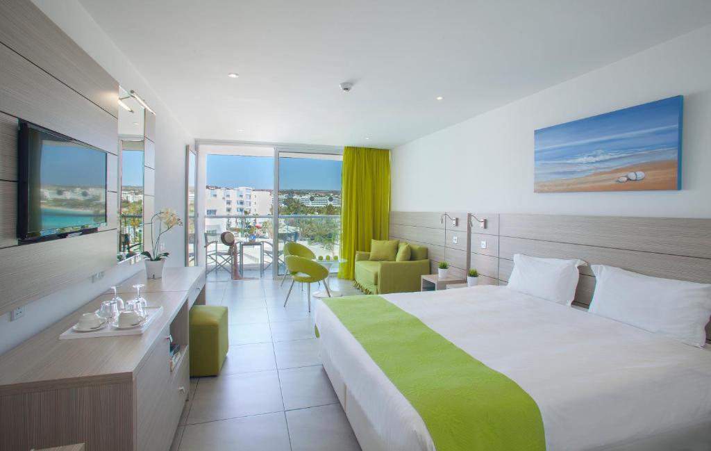 a hotel room with a large bed with a green blanket at Limanaki Beach Hotel & Suites in Ayia Napa