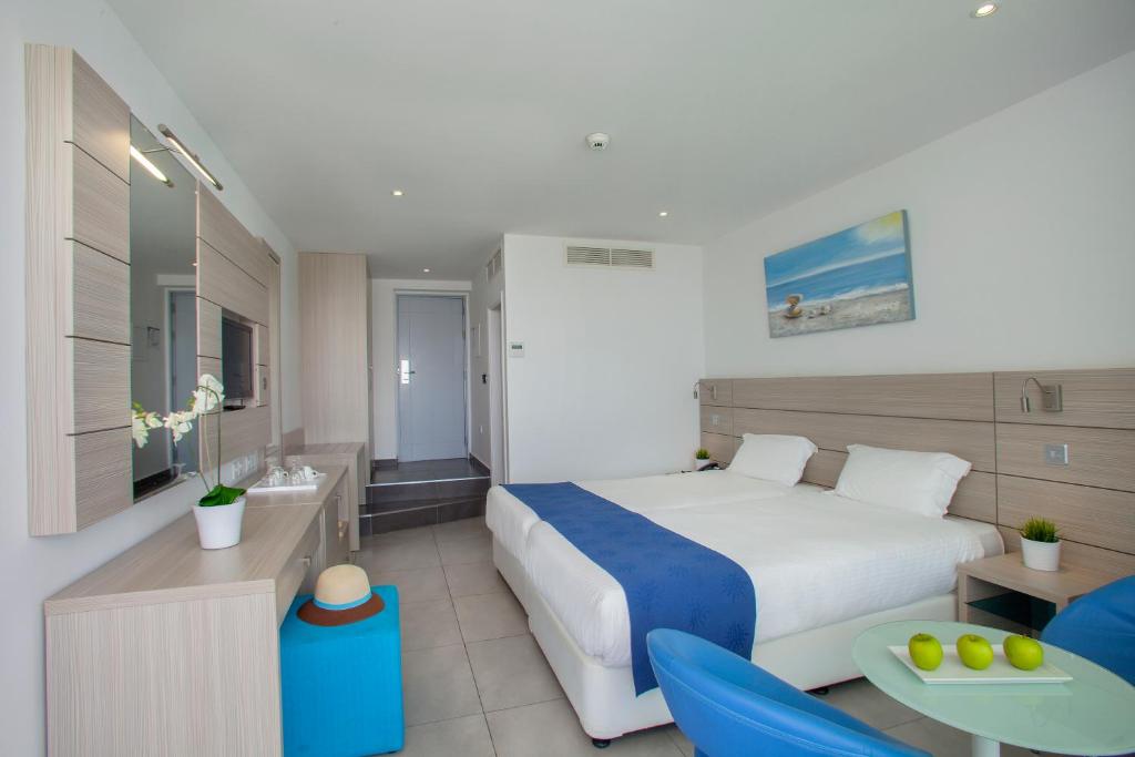 a hotel room with a bed and a table and chairs at Limanaki Beach Hotel & Suites in Ayia Napa