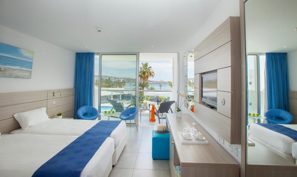 a hotel room with two beds and a balcony at Limanaki Beach Hotel & Suites in Ayia Napa