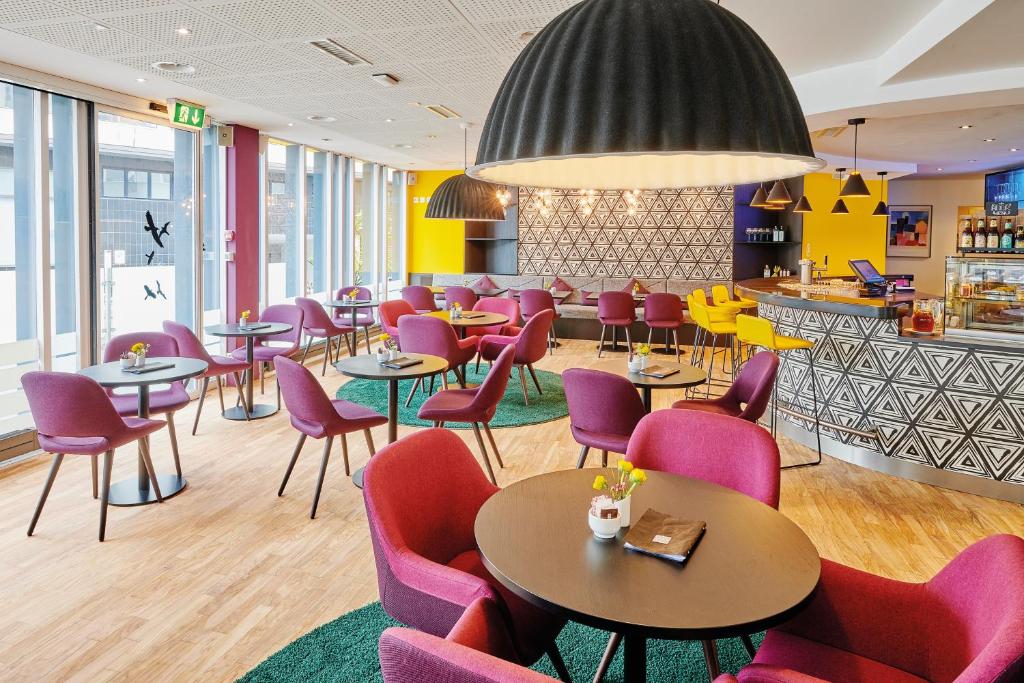 um restaurante com mesas e cadeiras roxas e um bar em Sorell Hotel Ador em Berna