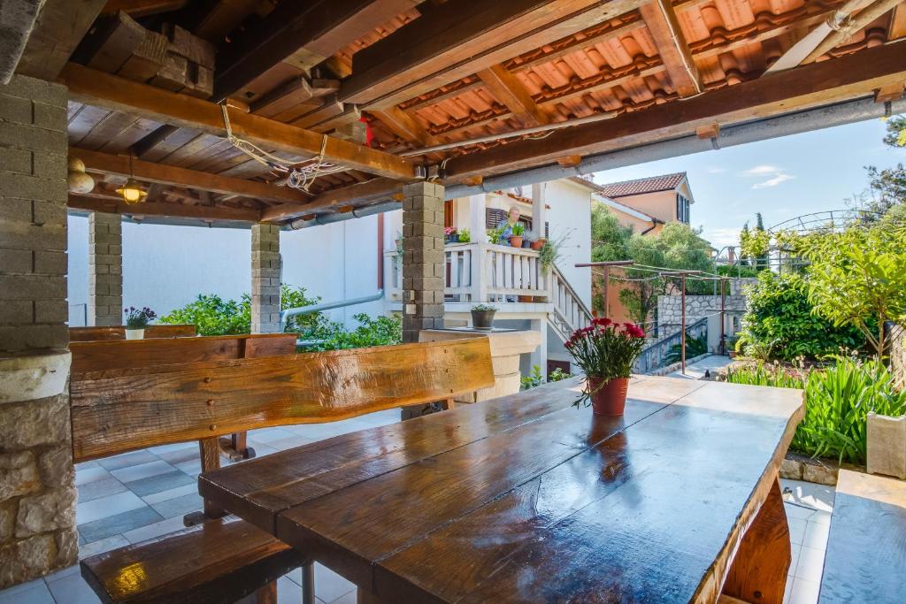 einen Holztisch und eine Bank auf einer Terrasse in der Unterkunft Apartmani Maris in Mali Lošinj