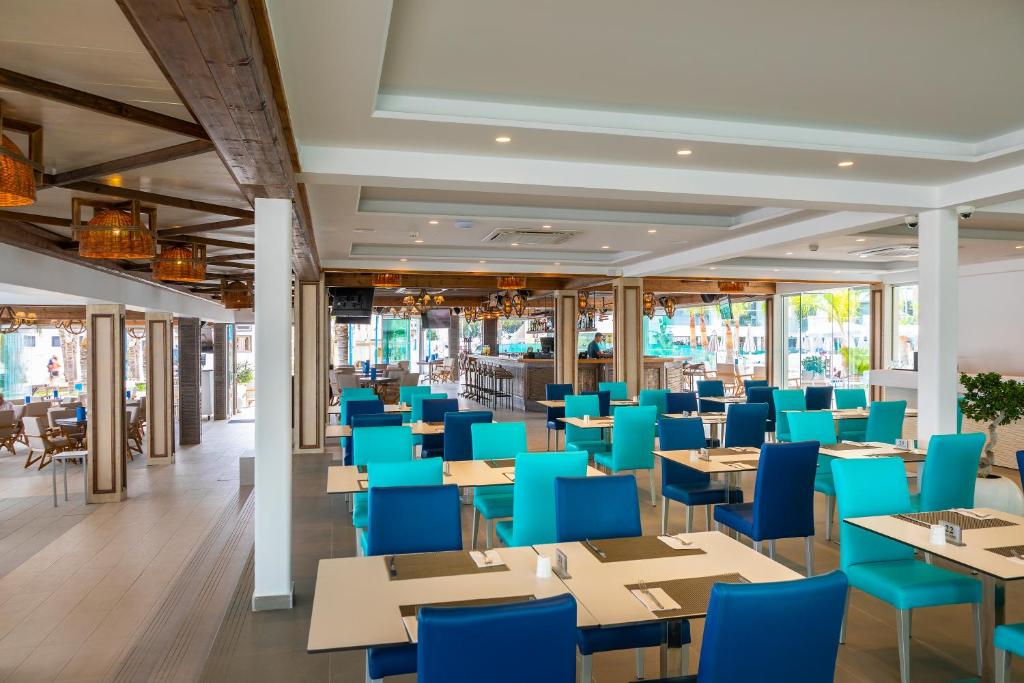 a dining room with blue chairs and tables at Limanaki Beach Hotel & Suites in Ayia Napa