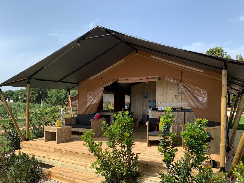 a gazebo with a black canopy and chairs and tables at Easyatent FKK Safari tent Ulika Naturist - clothes free in Poreč