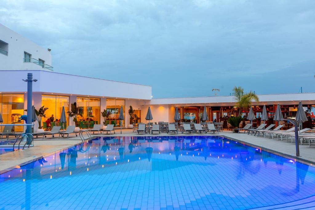 a large swimming pool with chairs and a hotel at Limanaki Beach Hotel & Suites in Ayia Napa
