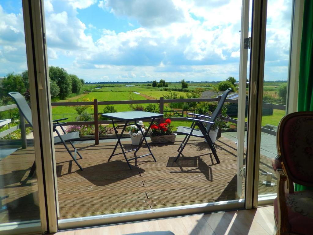 een patio met een tafel en stoelen op een balkon bij Villa Waterland in Den Ilp