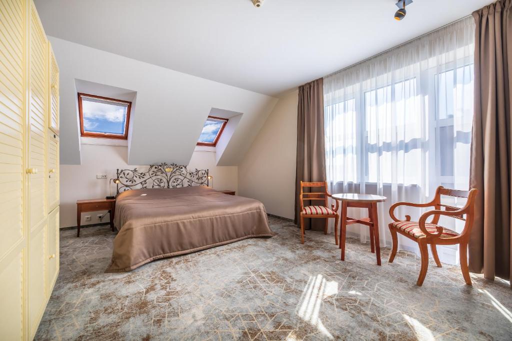 1 dormitorio con 1 cama, mesa y sillas en Vila Ieva, en Palanga