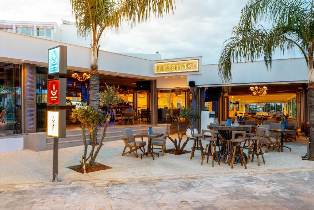 a restaurant with tables and chairs in front of a building at Limanaki Beach Hotel & Suites in Ayia Napa