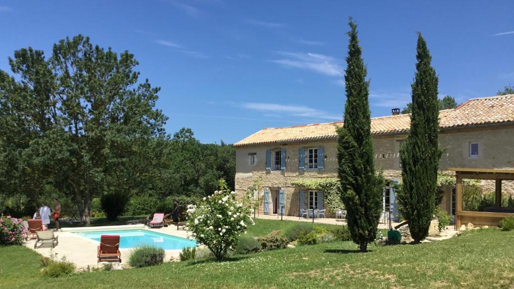 uma grande casa de pedra com piscina e árvores em Chambres d'Hôtes Le Val de la Garenne em Senouillac