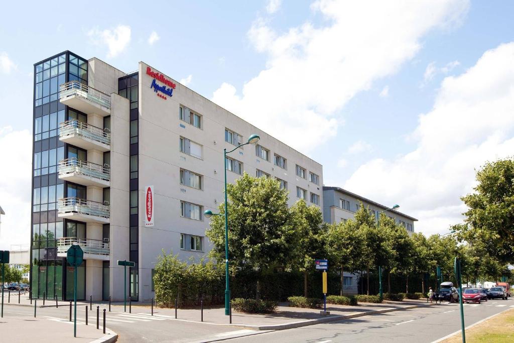 - un bâtiment blanc dans une rue de la ville arborée dans l'établissement Residhome Val d'Europe, à Montévrain