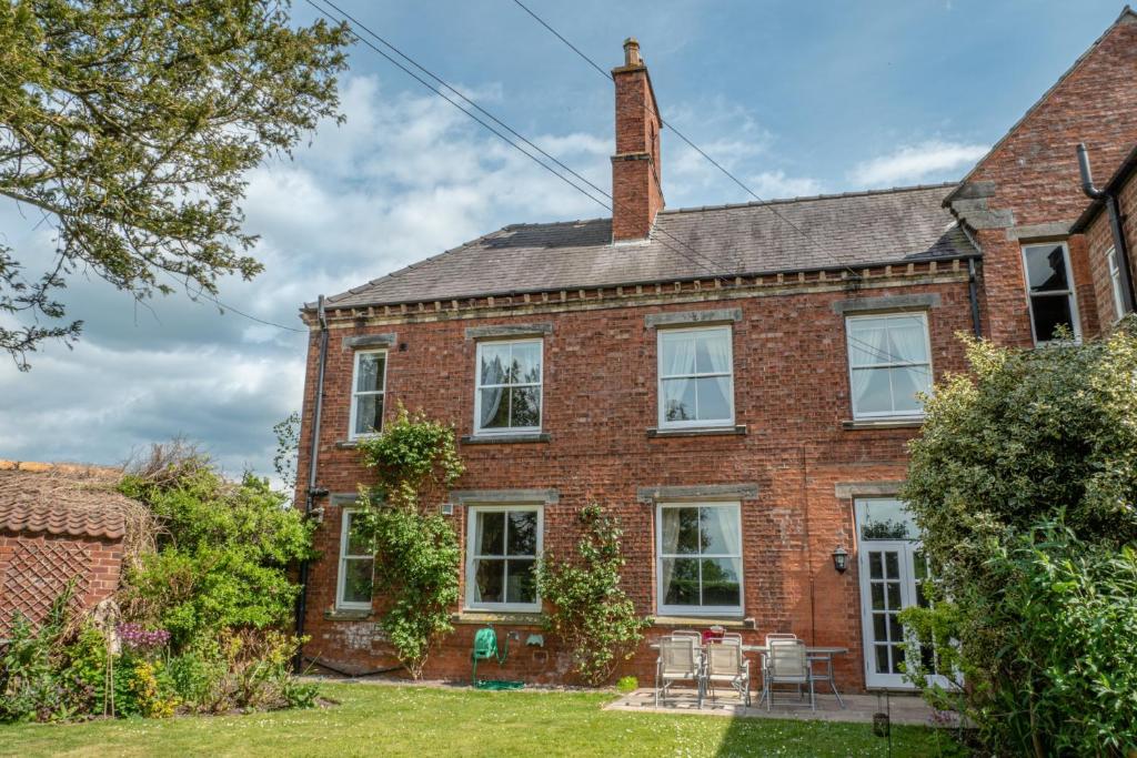 une maison en briques avec une cheminée au-dessus dans l'établissement Prince Rupert House at The Red House Estate, à York