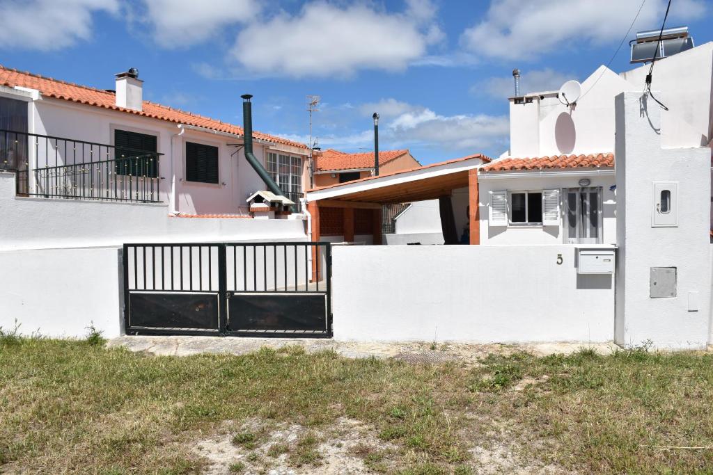 a white house with a black gate at Maison D'Almoinha in Sesimbra