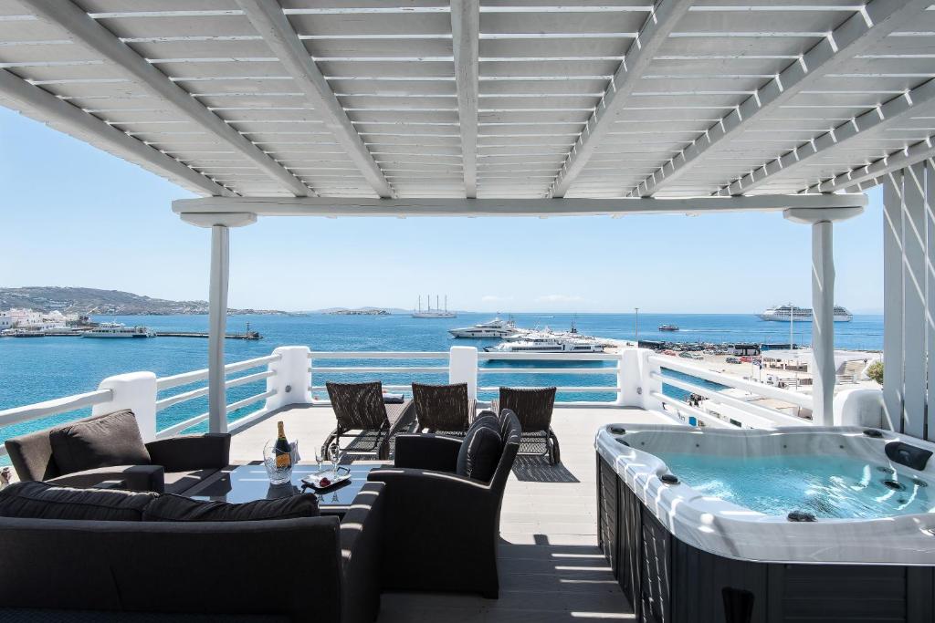 a lounge area with chairs, tables, and a balcony at Riva Suites in Mikonos