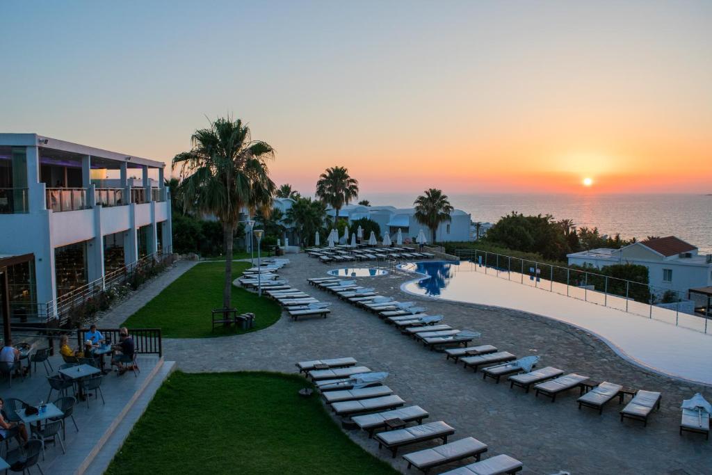 帕福斯的住宿－Theo Sunset Bay Hotel，享有带躺椅的度假胜地和大海的景致。
