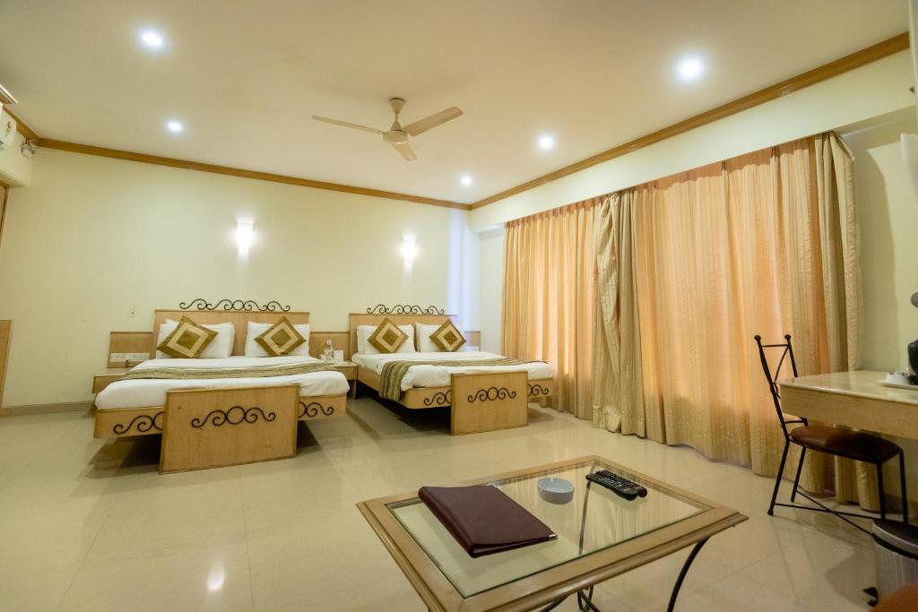 ムンバイにあるGarden Hotelのベッド2台とテーブルが備わるホテルルームです。