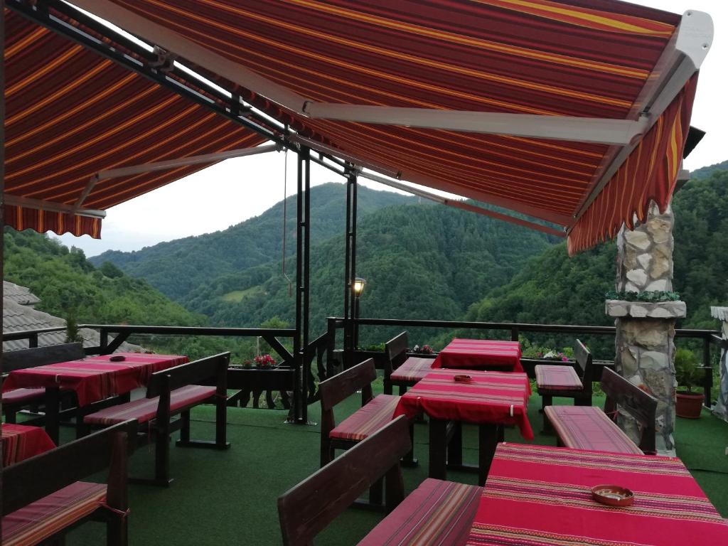 a restaurant with red tables and chairs with mountains in the background at Rodopsko Katche in Alamovtsi
