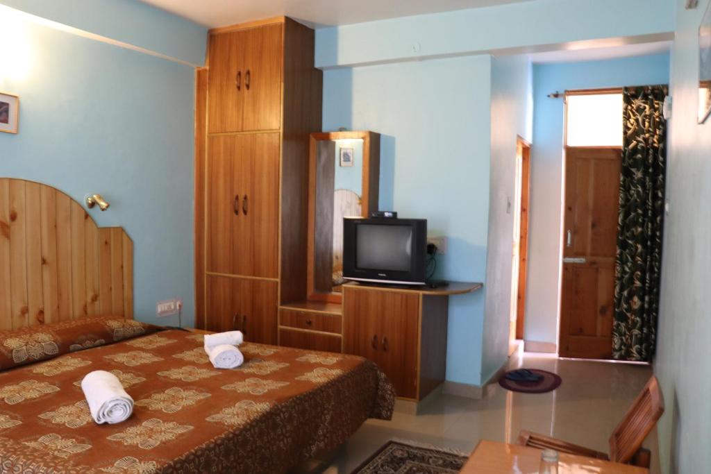 Habitación de hotel con cama y TV en Malis Apple Lodge, en Nagar