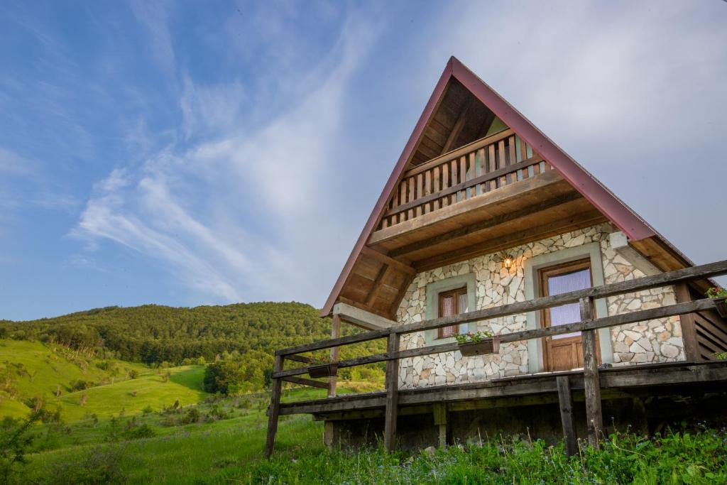 una cabaña de madera en una colina con un cielo azul en Etno Village Vojnik, en Šavnik
