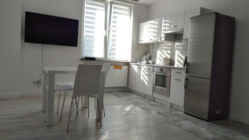eine Küche mit einem Tisch und Stühlen sowie einem Kühlschrank in der Unterkunft Apartament Białystok Center in Białystok