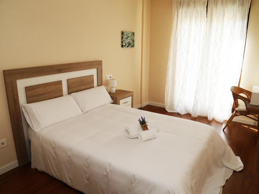 a bedroom with a large white bed with a candle on it at Apartamento turisticos Puente Romano P4 1-A in Salamanca