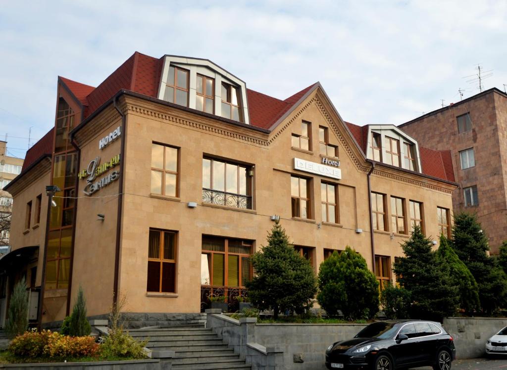 un edificio con un coche aparcado delante de él en Yerevan Deluxe Hotel en Ereván
