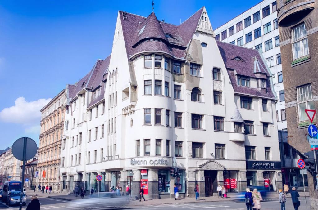 a white building with a brown roof on a city street at Brivibas Center Apartments in Riga