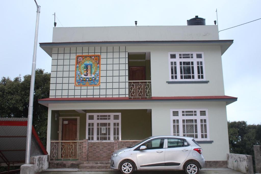 a white house with a car parked in front of it at Kitsel Homestay in Ravangla
