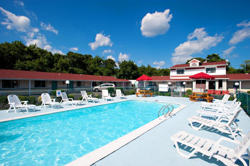 a white swimming pool with a blue chair and blue chairs at Economy Motel Inn and Suites Somers Point in Somers Point