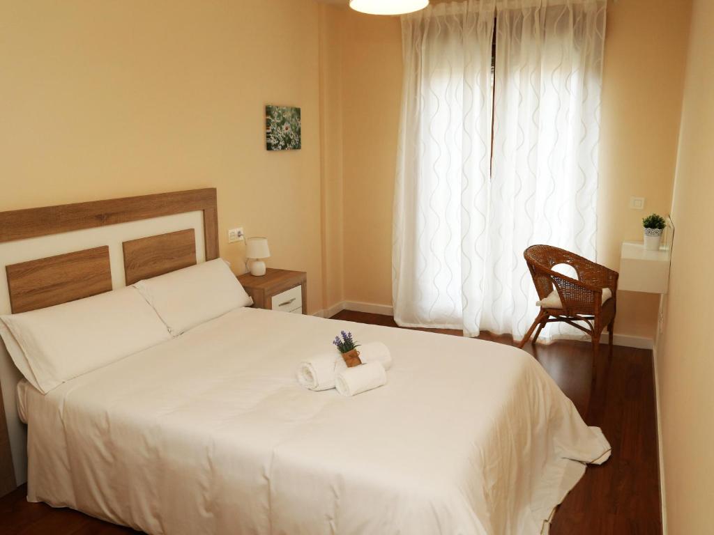 サラマンカにあるApartamentos turisticos Puente Romano Portal 4 Bajo -Aのベッドルーム1室(白いベッド1台、椅子、窓付)