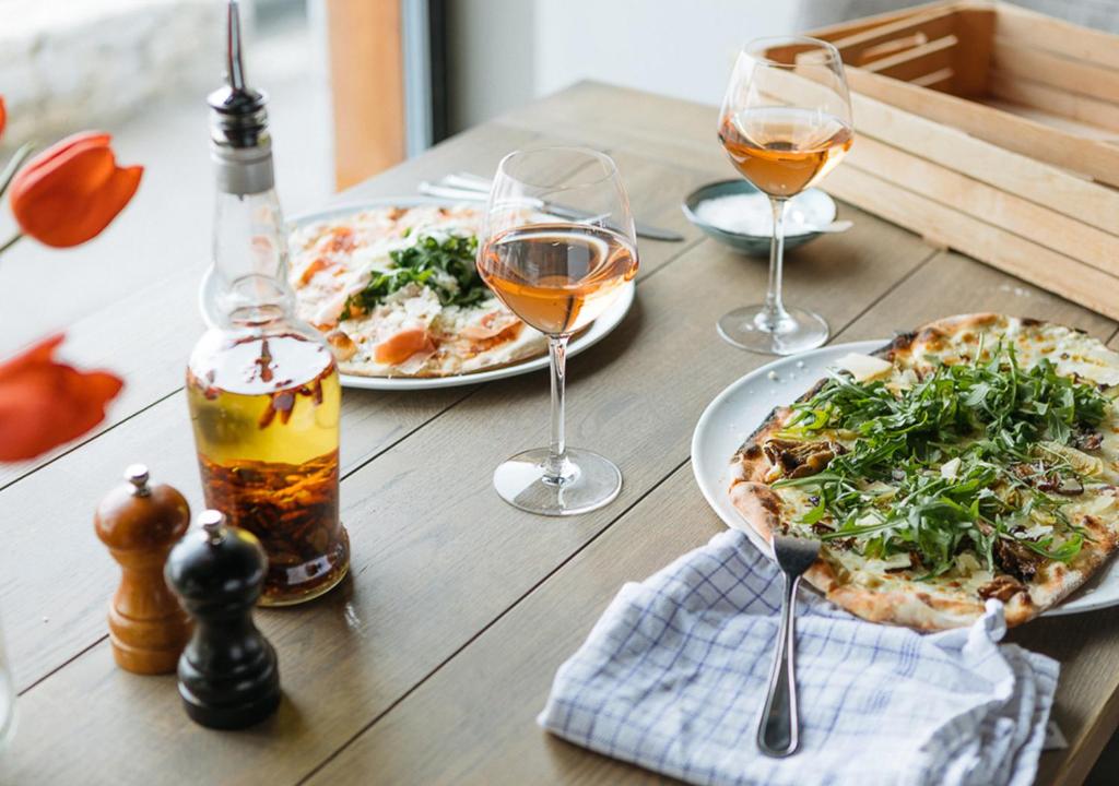 a wooden table with two pizzas and glasses of wine at Langley Hôtel Tignes 2100 in Tignes
