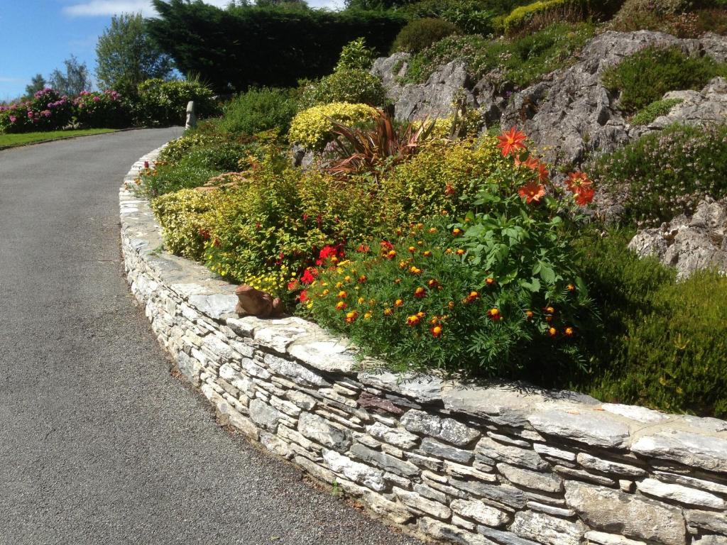 a stone wall with flowers on the side of a road at Rockcrest House in Kenmare