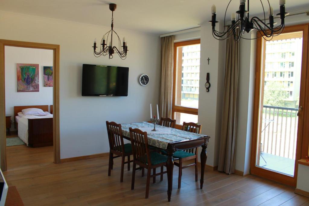 una sala da pranzo con tavolo, sedie e televisione di Ruta Marija a Druskininkai