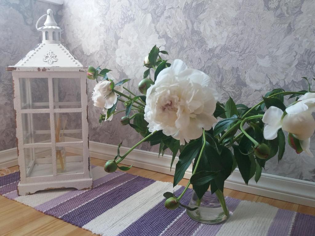 a vase with white flowers and a lantern on a table at Lille Lux Apartment in Viljandi