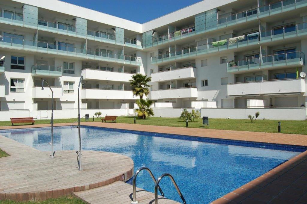 una piscina frente a un gran edificio de apartamentos en GMID IMMO Apartamento Portomarina, en Roses