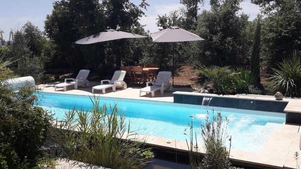 a swimming pool with two chairs and umbrellas at La Villa Provençale in Lorgues