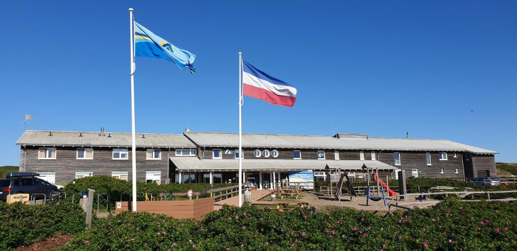 dos banderas volando delante de un edificio en Jugendherberge Westerland, en Westerland