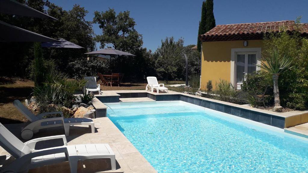 a swimming pool with chairs and a house at La Villa Provençale in Lorgues