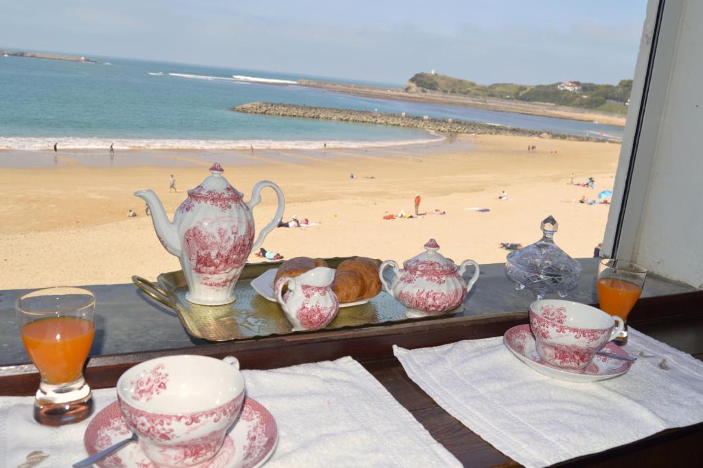 a table with tea sets and a view of the beach at Ayenac in Saint-Jean-de-Luz