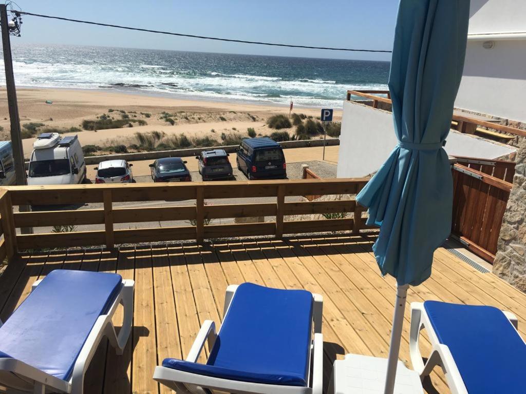 eine Terrasse mit Stühlen, einem Sonnenschirm und einem Strand in der Unterkunft Lucas House 1 in Aljezur