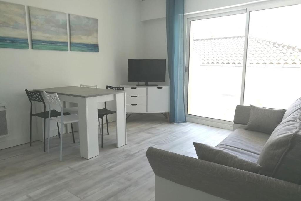 sala de estar con mesa y sofá en Appartement 4 couchages, 100 mètres de la mer ! en Les Sables-dʼOlonne