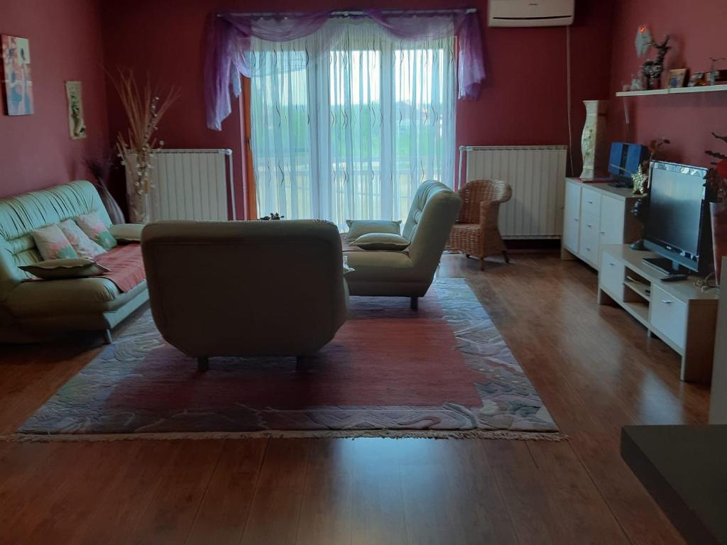 een woonkamer met een bank, stoelen en een televisie bij Apartment Brcko Distrikt in Brčko