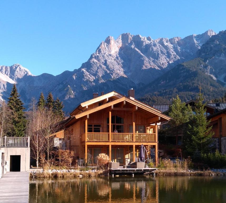 a house on a lake with mountains in the background at Chalet on the Lake in Hinterthal