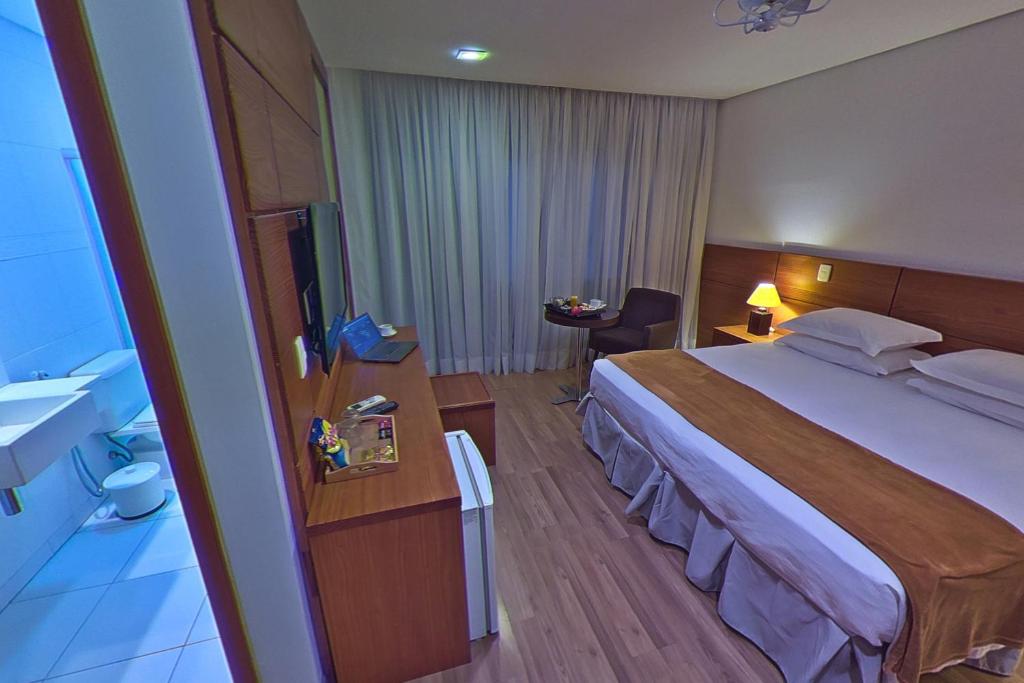 a hotel room with a large bed and a bathroom at Hotel Shelton in Serra Negra