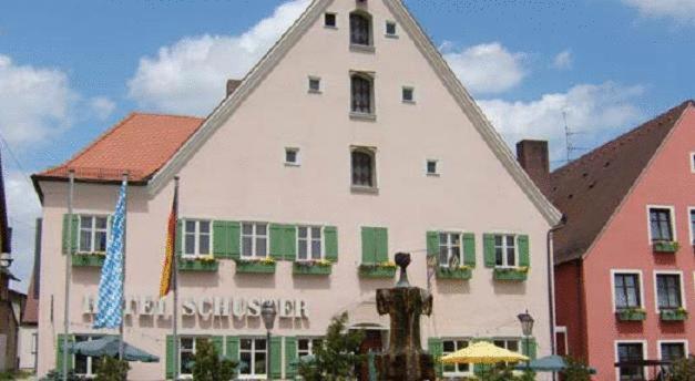 un grand bâtiment blanc avec des fenêtres vertes à volets dans l'établissement Hotel-Landgasthof Schuster, à Greding