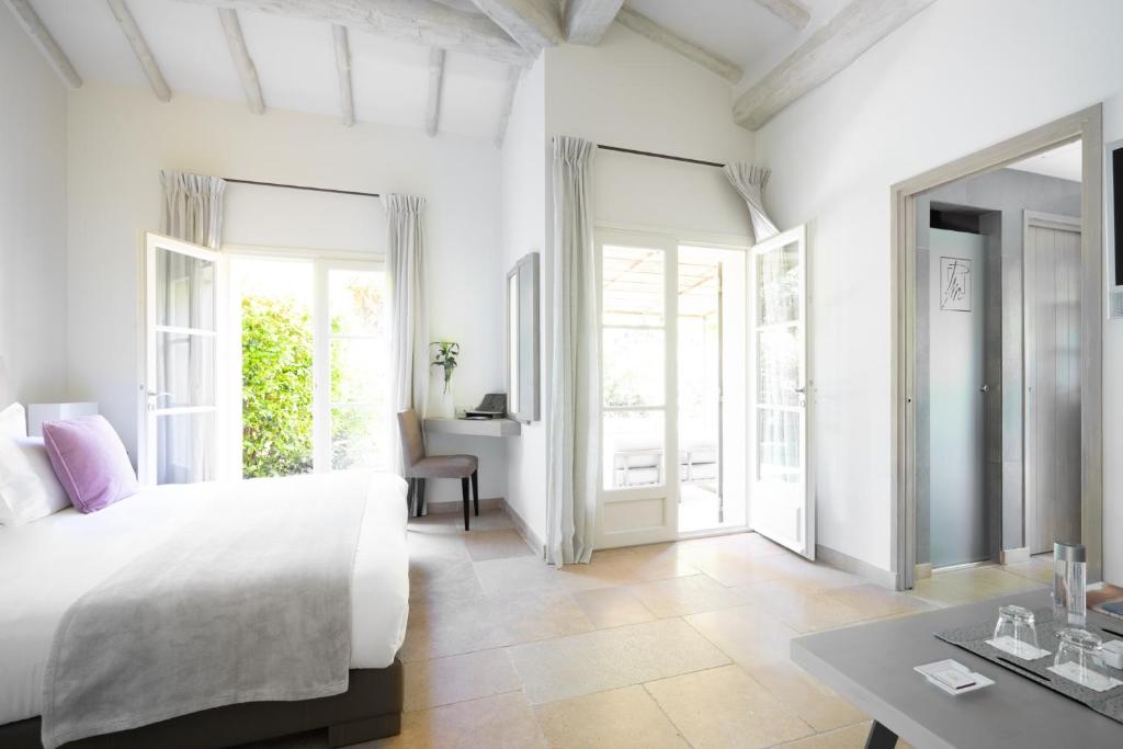 a white bedroom with a large bed and a table at Le Pre de la Mer in Saint-Tropez