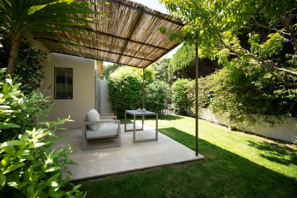 a pergola with a chair and a table in a yard at Le Pre de la Mer in Saint-Tropez