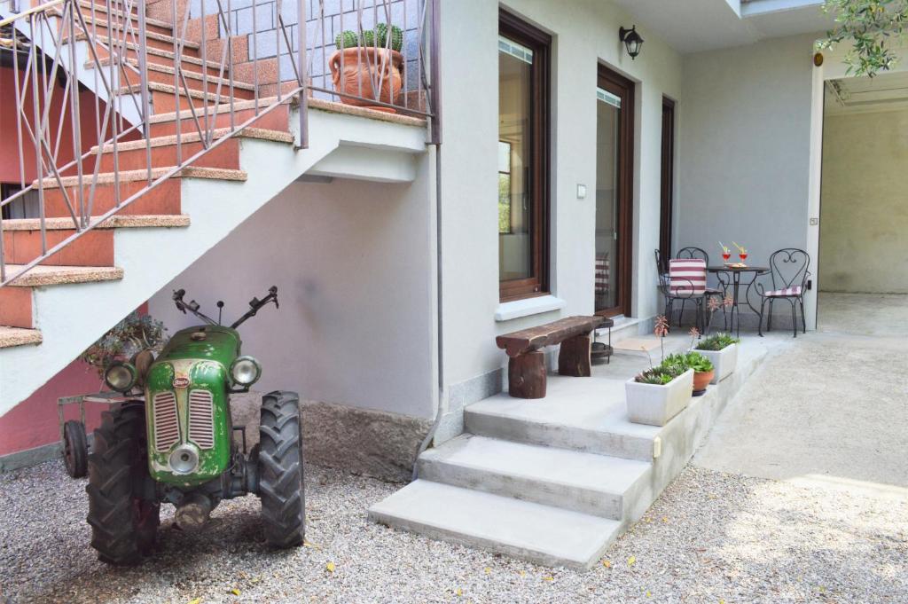 a green tractor parked next to a house with stairs at Casa Mamma Pina in Arco