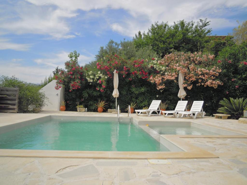 a swimming pool with two lawn chairs and a fountain at Petaloudes in Kamilari